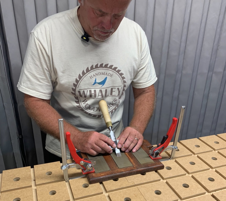 Woodworker using a honing guide to sharpen a chisel on a combination waterstone — beginner chisel sharpening technique