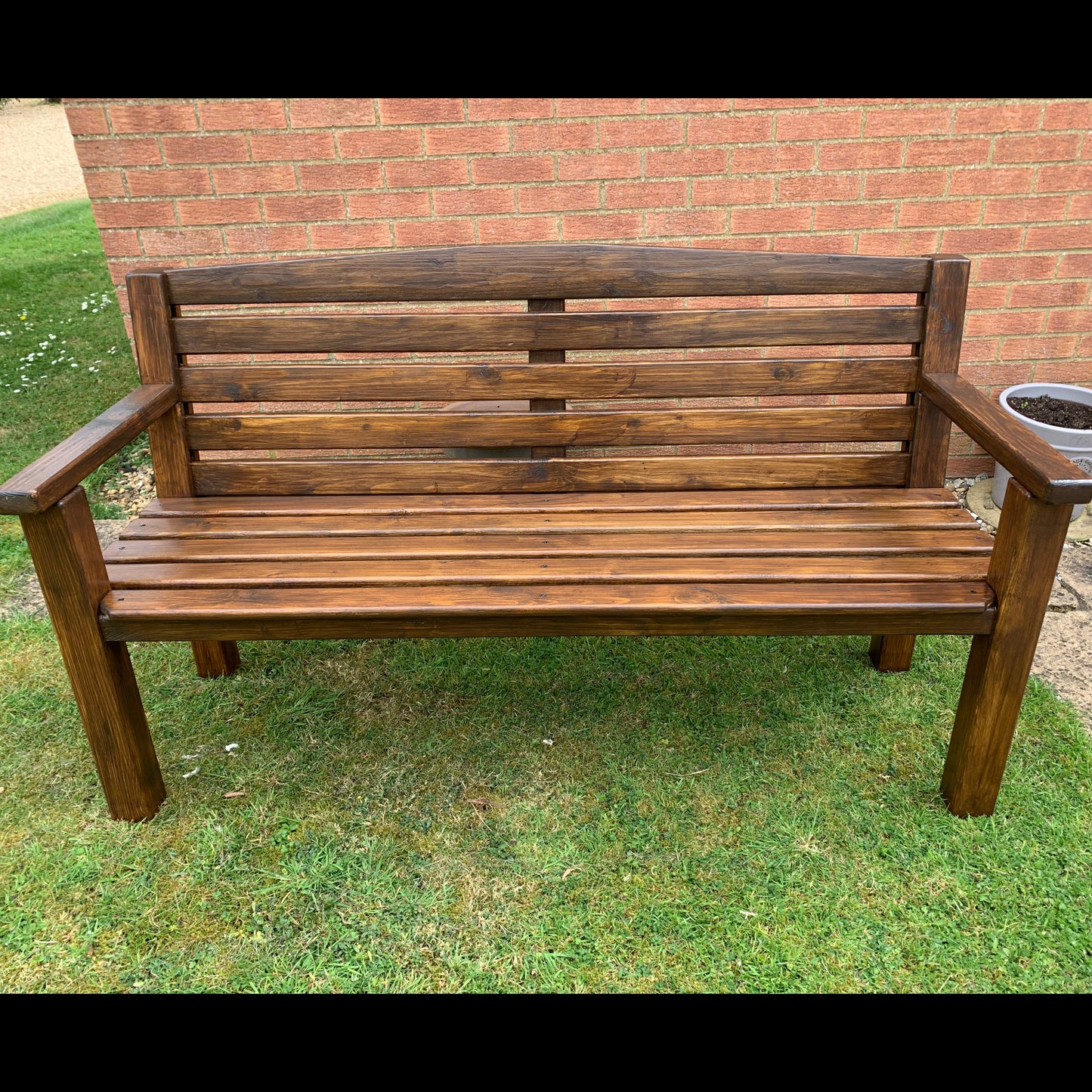 Handmade dark oak garden bench in garden setting, front view