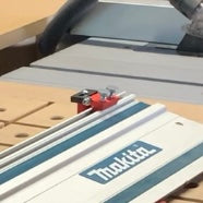 Close-up of a track-saw guide rail aligned with red bench dog stops on a workbench.