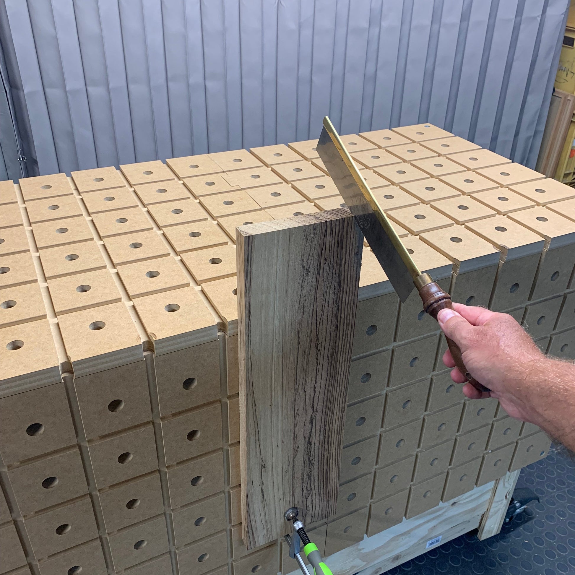 HDS Workbench Top – hand saw cutting a board clamped upright against the hold down system workbench top, made in the UK