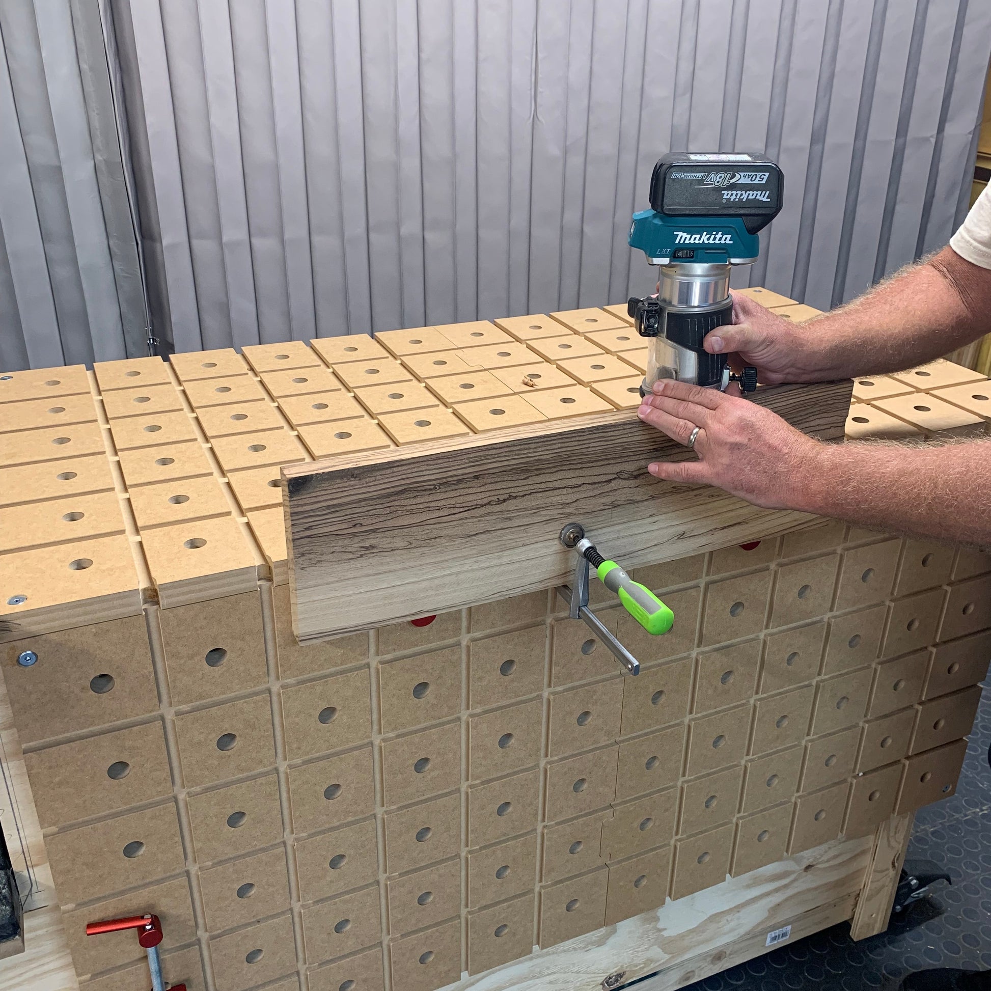 HDS Workbench Top – Makita trim router routing the edge of a board clamped to the hold down system workbench top, made in the UK