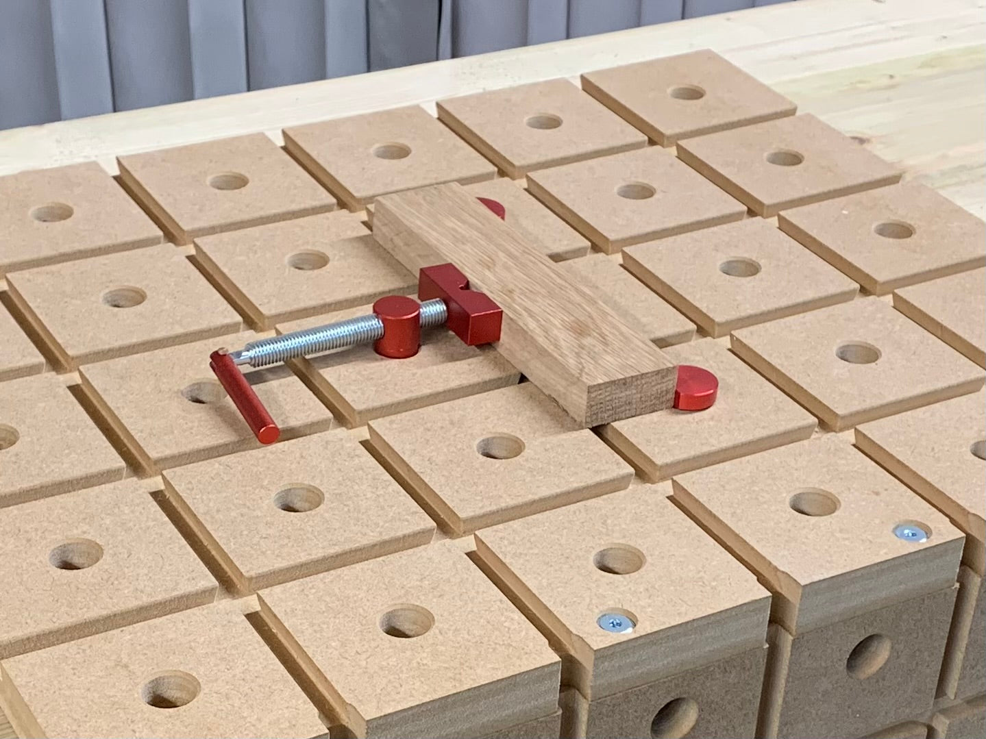 A piece of oak being secured on the HDS hold down system using a combination of bench dogs and a bench dog clamp