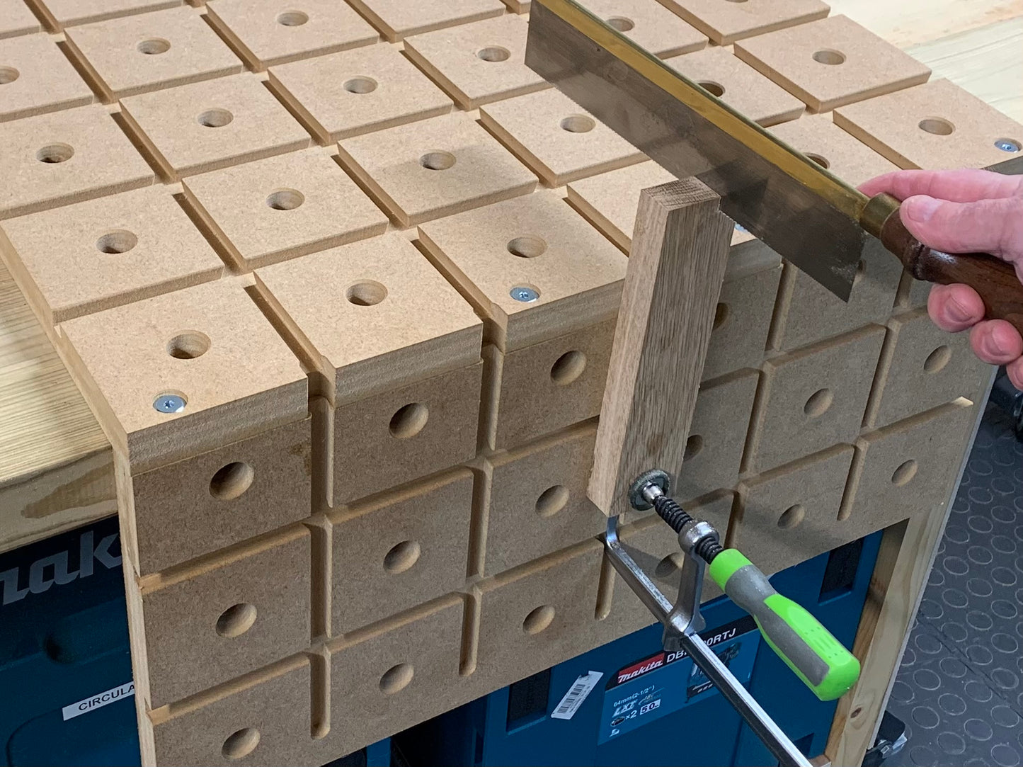 Person using a gentleman saw to cut A piece of oak being secured by a standard track clamp on the HDS hold down system
