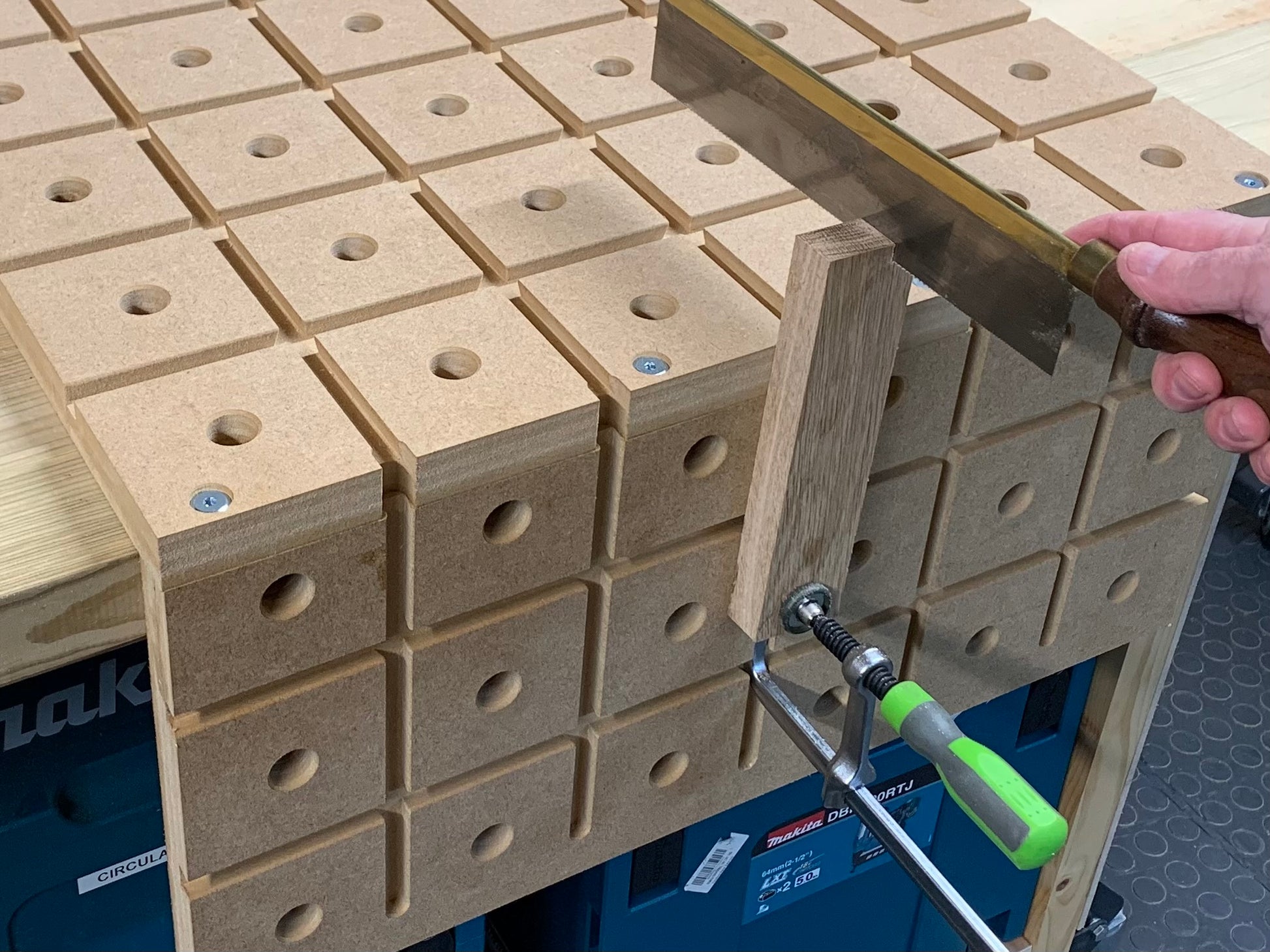 Person using a gentleman saw to cut A piece of oak being secured by a standard track clamp on the HDS hold down system