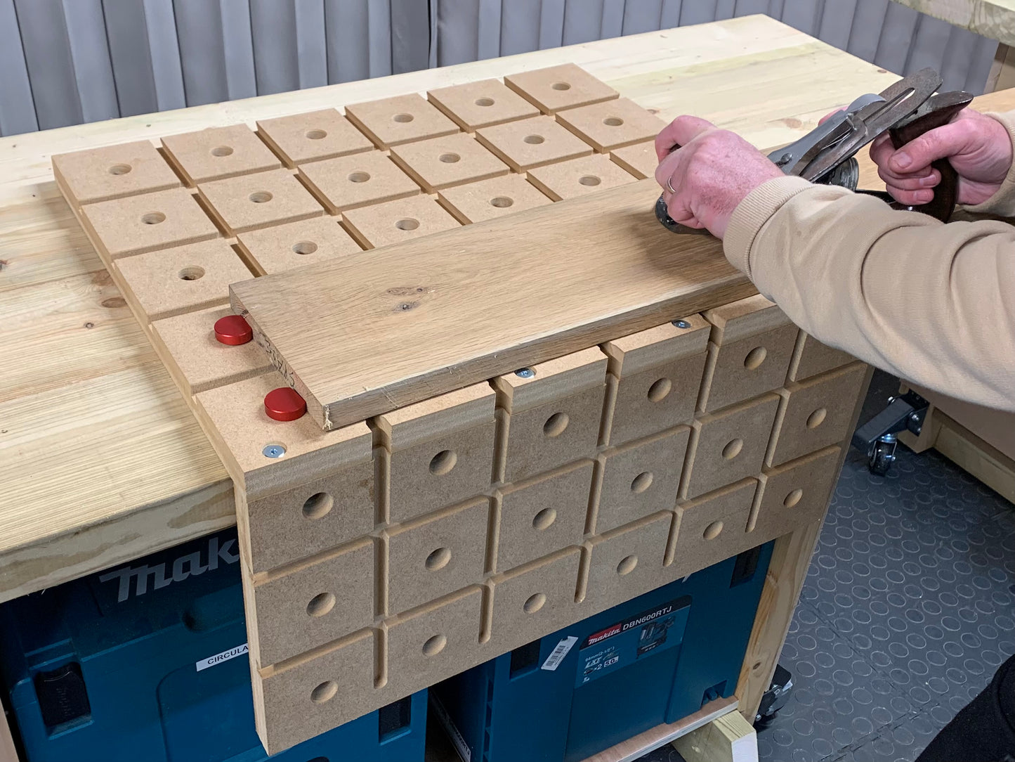 Woodworker using a Stanley number five plane on a piece of oak secured by bench dogs on the HDS holddown system