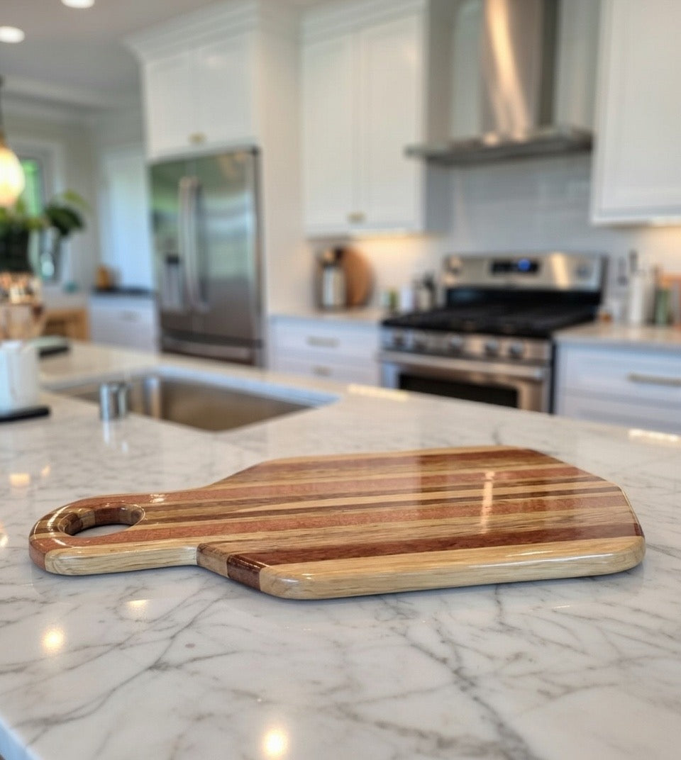 Handmade hardwood charcuterie board with handle on a kitchen island counter by Whaley Woodworks